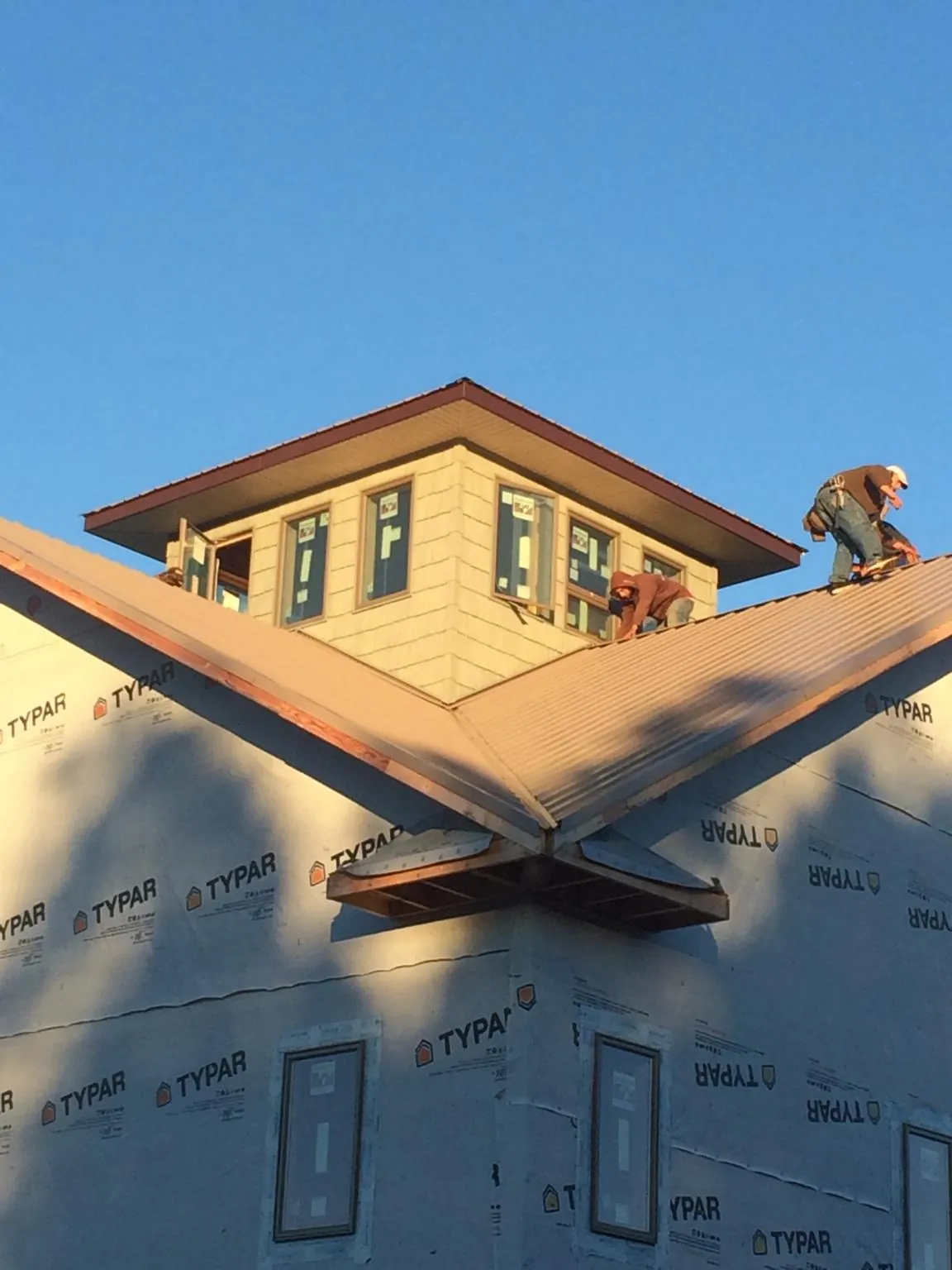 Roofers working around a rooftop cupola on a new metal roof at sunset — Roof Waterproofing in Verona by Roofing Brothers